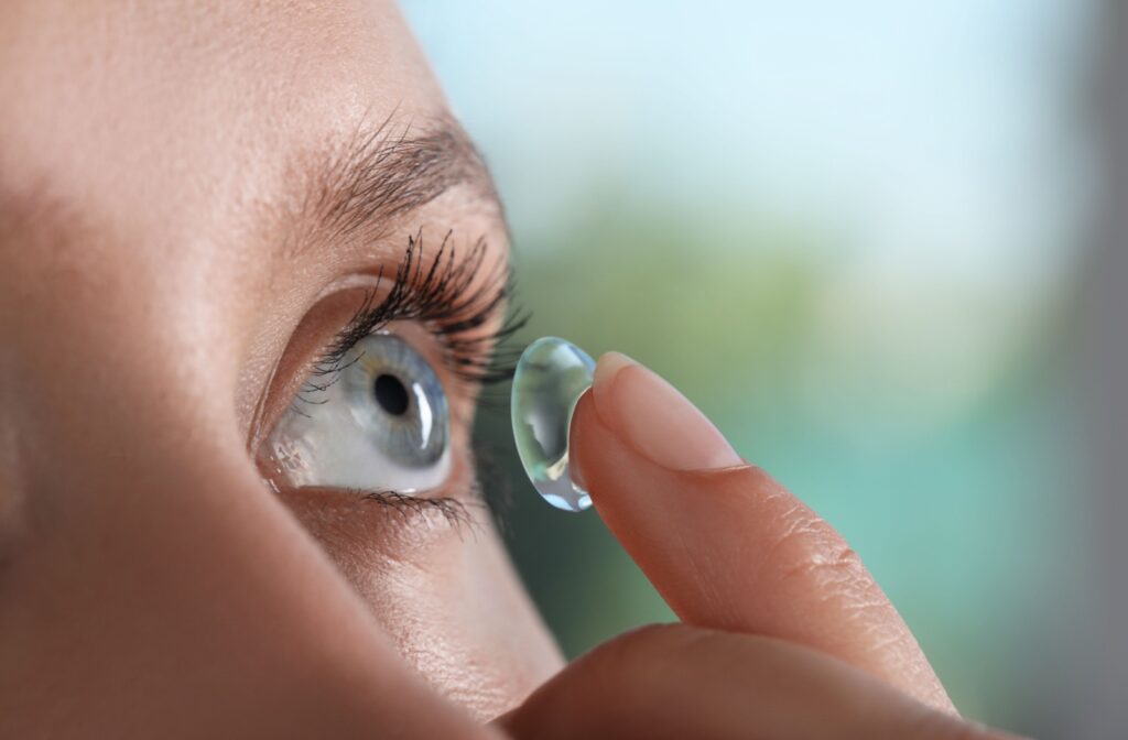 Close-up of a person inserting a daily contact lens into their left eye.
