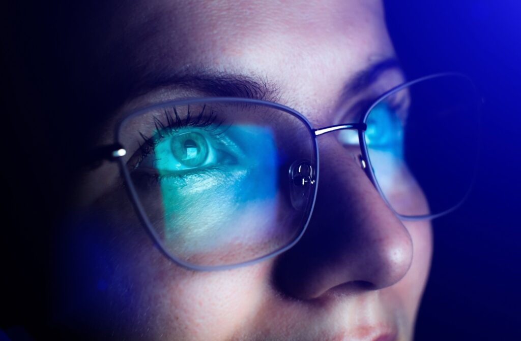 A bright computer screen reflects off a person's eyeglasses.