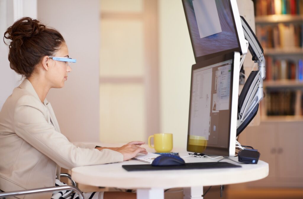 A professional wears blue light glasses, optimizes their workspace, and maintains good posture while working on the computer.
