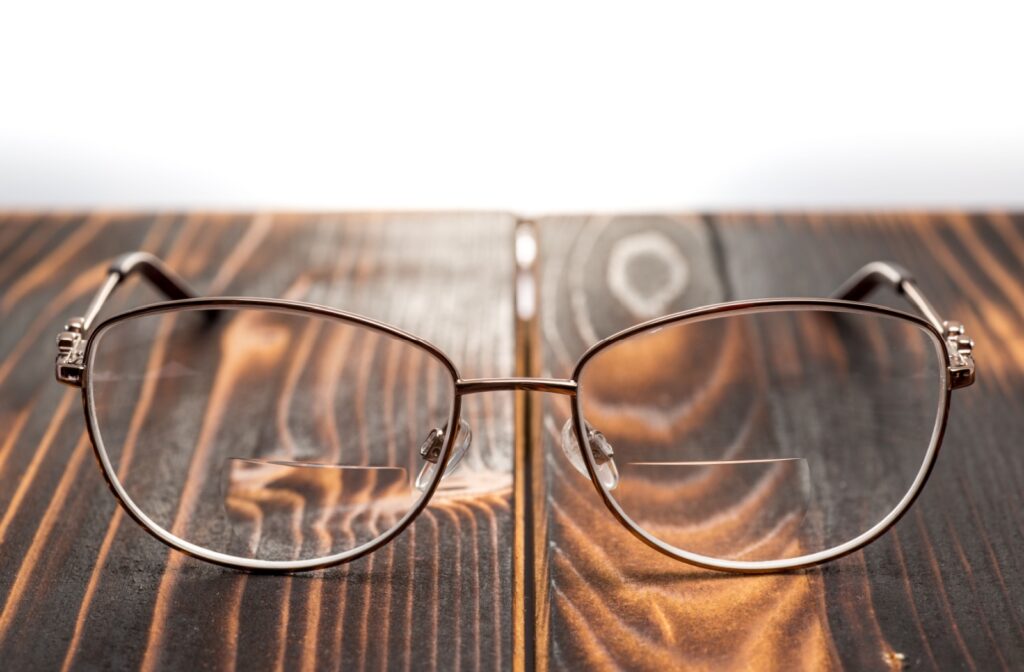 Eyeglasses with a metal frame and bifocal lenses sitting on wooden surface