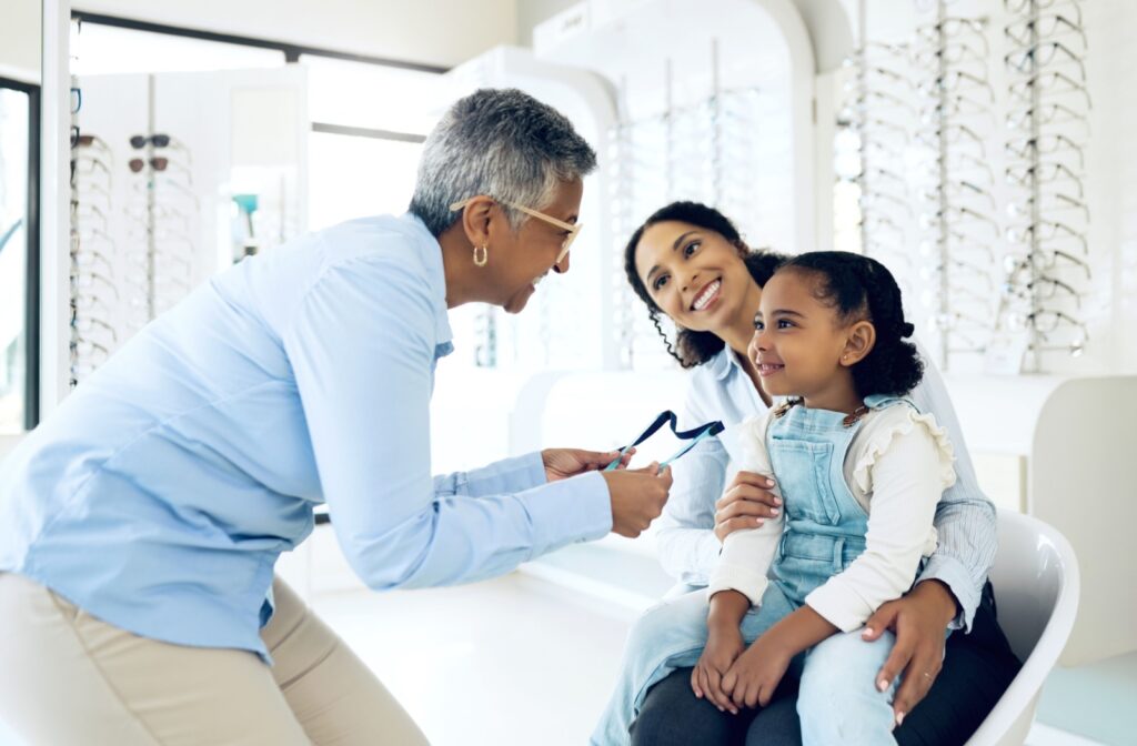 An optometrist talking to a parent and child during a comprehensive eye exam as a part of preventative health care.