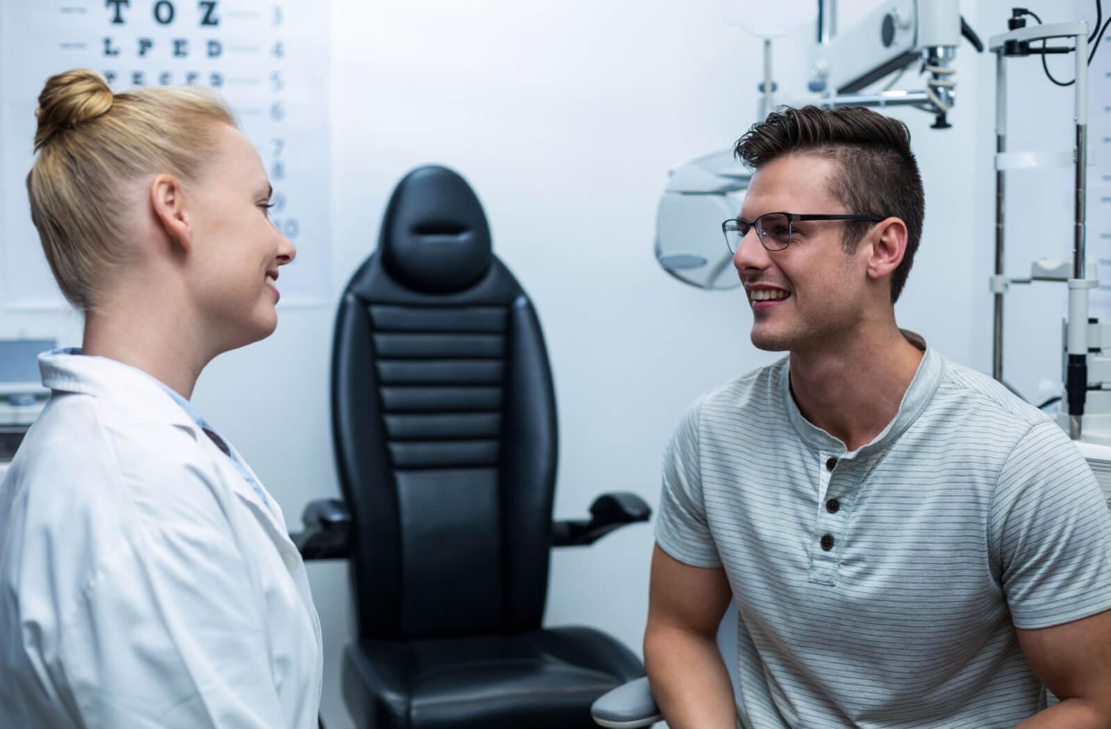 An eye doctor and patient discussing medical history and insurance information before an eye examination.